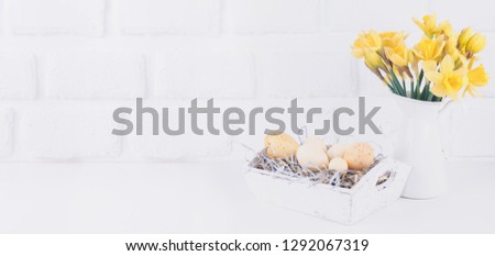 Jar with narcissuses and eggs at the white brick background. Spring and Easter concept. Horizontal, wide screen banner format
