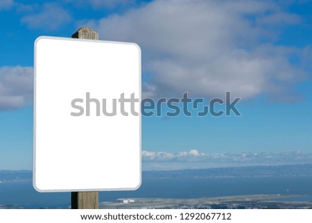 Empty rectangle advertisement space on the wooden post overlooking water and mountains under cloudy sky