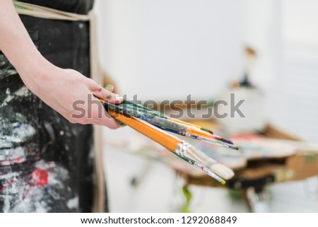 Artist's tools on the easel. Brushes, paints and canvas. White background, art studio.