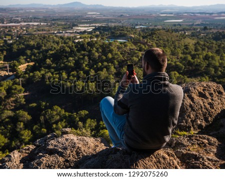 young guy with beard take a picture a landscape
