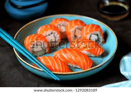 Homemade sushi rolls Philadelphia and nigiri in a blue plate on a black background.