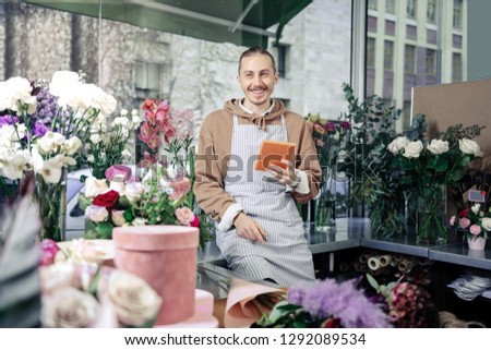 Be positive. Delighted male person keeping smile on his face while creating idea for bouquet