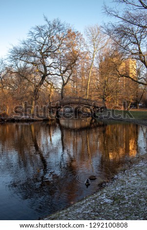 Pond in the park with romantic bridges, church in winter in Leipzig with blue sky