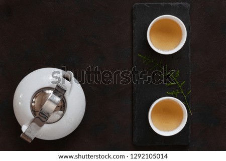 White porcelain Asian tea set with green tea Milk Oolong on black stone desk. Close up, top view.