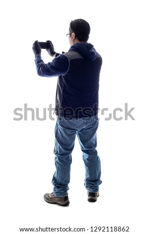 Male hiker or tourist doing mobile photography with a cell phone camera.  Isolated on a white background for composites or copyspace. 
