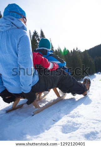 mother snow sledging on the ski slope with two sons on a sunny day