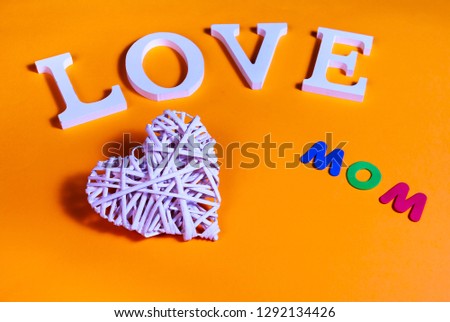 75 degrees picture of white word love, white heart in relief and colored word mom, in orange background