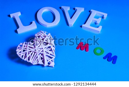 75 degrees picture of white word love, white heart in relief and colored word mom, in blue background