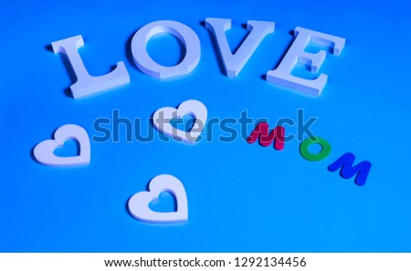 75 degrees picture of white word love, three white hearts and colored word mom, in blue background