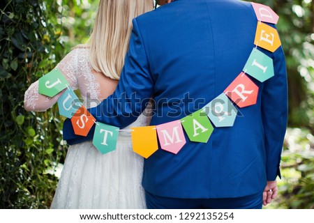 Bride and groom holding "Just married" garland