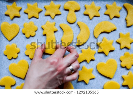 A lady hand puts tasty cookies with butter on baking paper. Cakes are in different shapes. Moon, star, heart, mushroom - Image