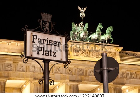 A Pariser Platz street sign with the iconic Brandenburg Gate pictured in the background, in Berlin, Germany.