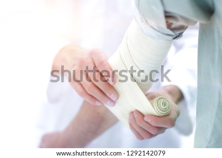doctor applying elastic bandage on the elbow of the patient.