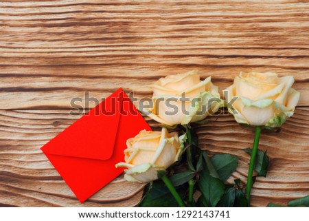 Three red roses and a card on a wooden table