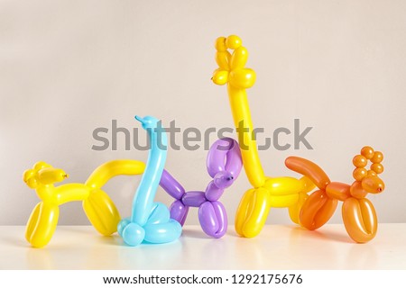 Animal figures made of modelling balloons on table against color background