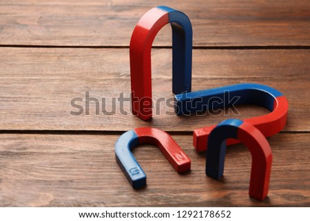 Red and blue horseshoe magnets on wooden background. Space for text