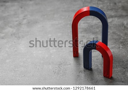 Red and blue horseshoe magnets on grey background. Space for text