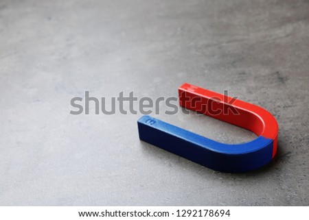 Red and blue horseshoe magnet on grey background. Space for text