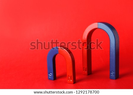 Red and blue horseshoe magnets on color background. Space for text