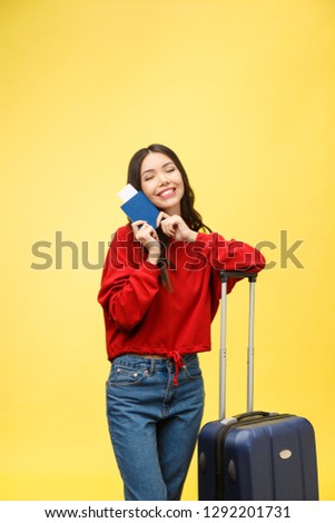 Woman travel. Young beautiful asian woman traveler with suitcase and passport on yellow background