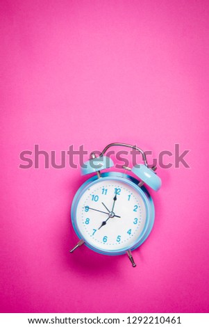 Beautiful retro blue pastel alarm clock on a vibrant pink background
