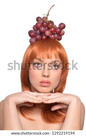 Portrait of a redhead young woman with red grapes on head 
