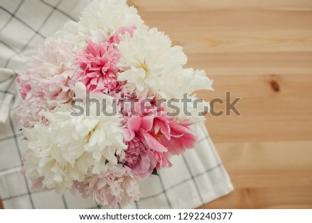 Beautiful peonies in vase and petals on cloth on rustic wooden table top view with space for text. Hello summer. Happy mothers day greeting card. International Women's Day.