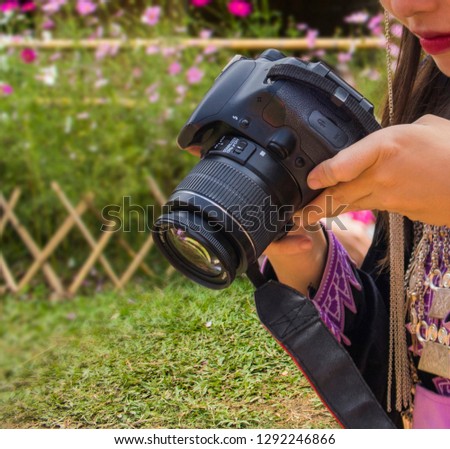 Pretty girl using a digital camera to taking pictures of flowers. 