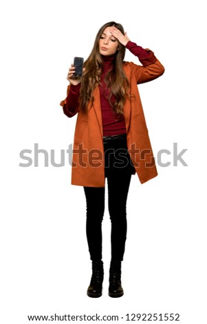 Full-length shot of Young woman with coat with troubled holding broken smartphone on isolated white background