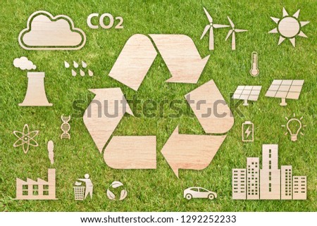 Ecology concept: recycling. A white recycling shape and other small white ecology shapes superimposed on grass background.