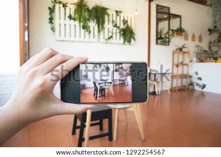 Hand using smart phone take a photo inside a cafe.