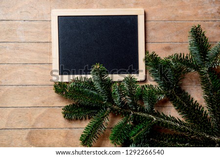 Pine tree branch and blackboard on wooden table. Side view
