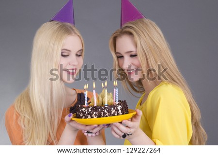 beautiful teenage girls with birthday cake over grey