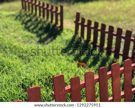 small decorative wooden fence in grass.