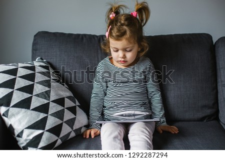 Sad little girl with a digital tablet at home