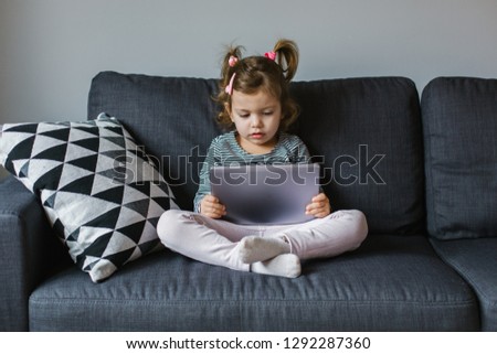 Female child using digital tablet and sitting on the sofa