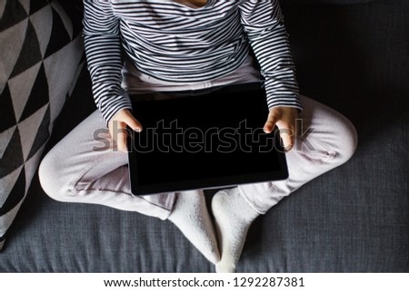 Top view of little child sitting on sofa and using a digital tablet