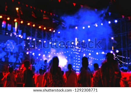 Blurred image many people are enjoying with decorative lighting and smoke effect on stage in outdoor concert at night 