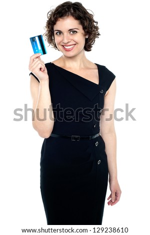 Cheerful fashionable young woman holding up credit card.