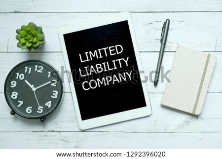 Business concept. Top view of plant,clock,pen,notebook and tablet written with Limited Liability Company on white wooden background. Royalty-Free Stock Photo #1292396020