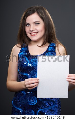 Attractive young woman in a blue dress. Woman holds a poster. On a gray background