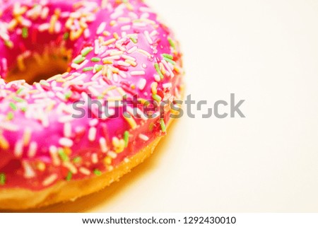 Bright donut in a pink glaze with a multi-colored rainbow sprinkle on a yellow background. Sweets and desserts. Minimalistic background with clean place for the inscription. Copy space. Soft focus.