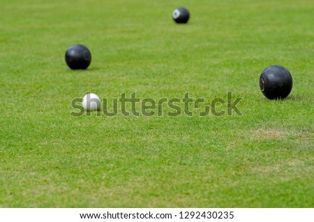 Lawn bowls or outdoors bowling outside or flat green bowling on a green field with balls. Playing sport with matt, jack and balls in the summer - image.