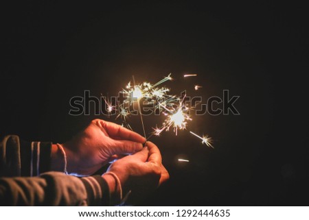 Abstract sparklers background bright festive Christmas and happy new year the man hold hand sparkler motion blurred in wind at winter night for celebration and hope background.Vintage film tone.