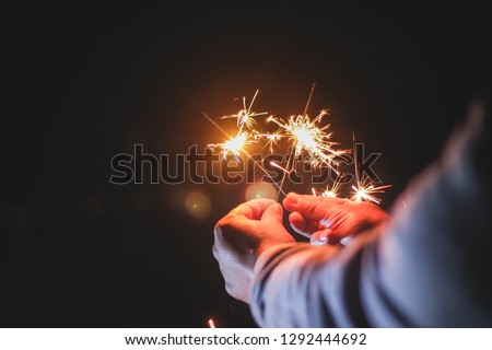 Abstract sparklers background bright festive Christmas and happy new year the man hold hand sparkler motion blurred in wind at winter night for celebration and hope background.Vintage film tone.