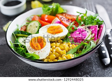 Fresh salad. Bowl with fresh raw vegetables - cucumber, tomato, watermelon radish, lettuce, arugula, corn and boiled egg. Healthy food. Vegetarian buddha bowl.