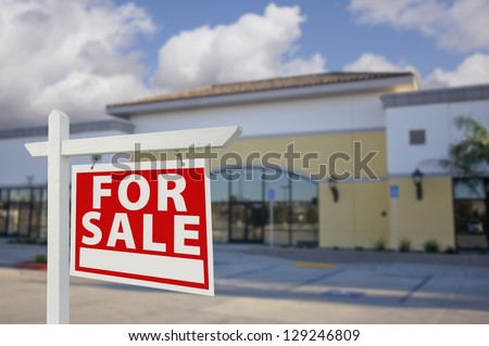 Vacant Retail Building with For Sale Real Estate Sign in Front.
