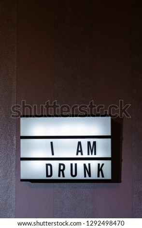 Message Sorry I Am Drunk on illuminated board. Drinking alcohol concept with text. Daylight from window. Room interior. Black letters I Am Drunk on purple wallpaper wall.
