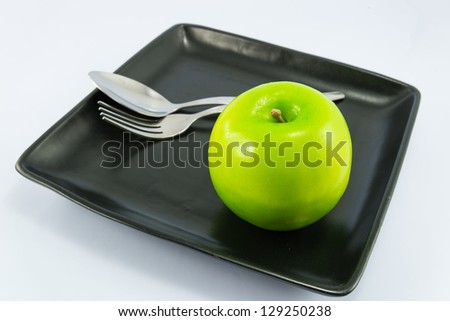 Apple on dish with white backgrounds.