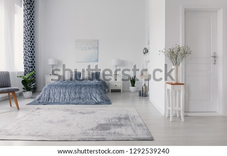 New york style bedroom design with double bed, white bedside tables with lamps, plush carpet and velvet bedding on bed, real photo with copy space